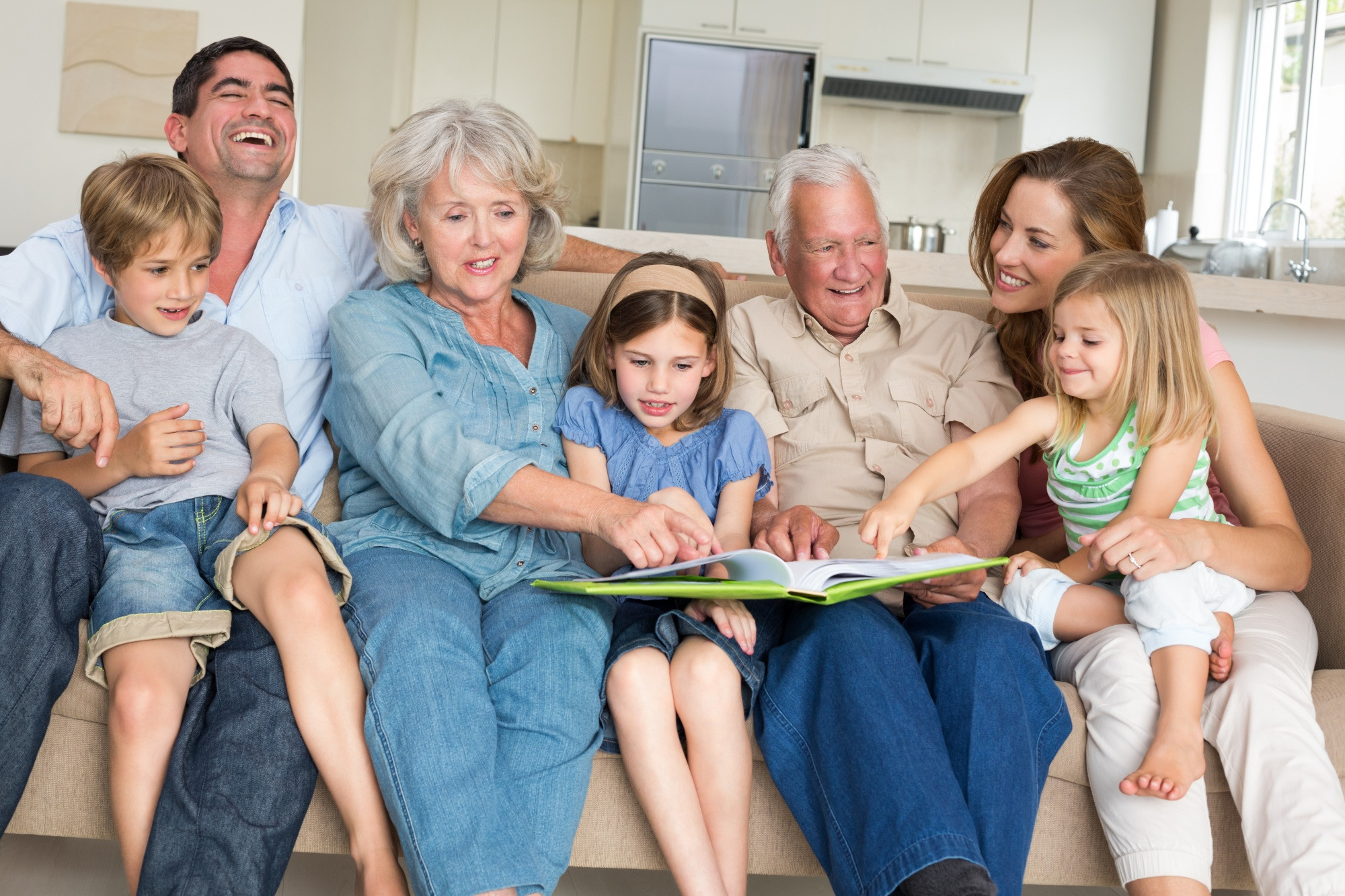 Three generations of a family sitting together, looking through a photo book